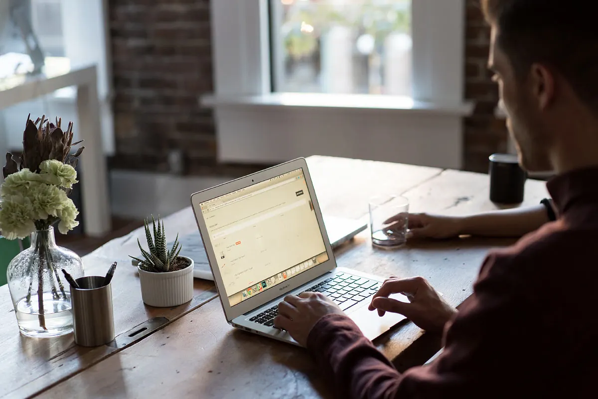 A small business owner working at a laptop on a wooden table